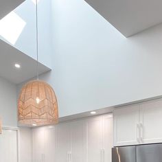 a modern kitchen with white cabinets and stainless steel appliances, including a bamboo pendant light fixture