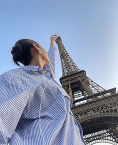 a woman standing in front of the eiffel tower looking up into the sky