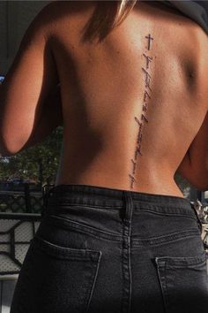 the back of a woman's body with a cross tattoo on her lower back