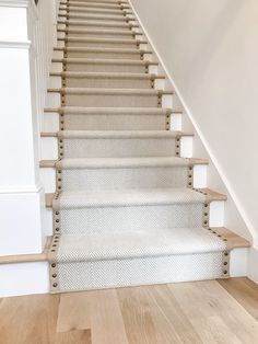 a white staircase with beige carpet and wooden handrails