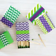 matchboxes made out of matchesticks with green and purple designs on them