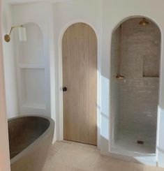 a bath tub sitting in the middle of a bathroom next to a wooden door and window