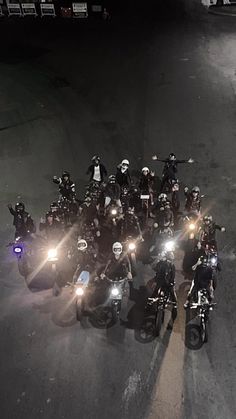 a group of motorcyclists riding down the street at night with their lights on