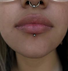 a woman wearing glasses with a nose ring on her nose and piercing in the middle