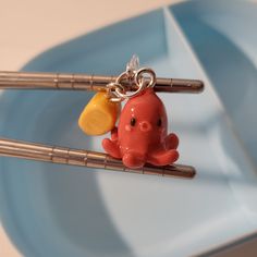 an orange and yellow octopus keychain sitting on top of two chopsticks