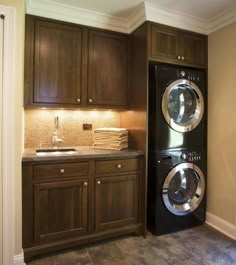 a washer and dryer are in the corner of this laundry room with dark wood cabinets