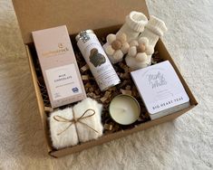 an open box with candles, soaps and other items in it on a white carpet