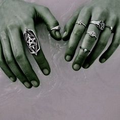 two hands are shown with rings on their fingers, one is green and the other is white