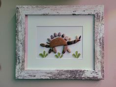 a shadow of a lizard in a white frame on the wall next to a teddy bear