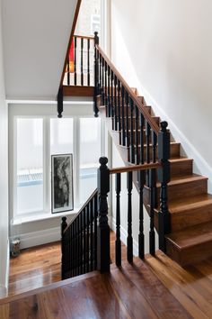 a staircase with wooden handrails next to a window and pictures on the wall