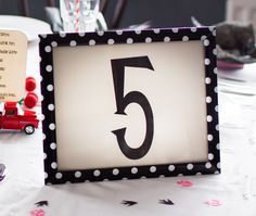 a table with a sign that says 5 on it and a toy truck in the background