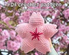 a hand holding a pink knitted flower with the words, pdf crochet pattern cherry blossom pillow