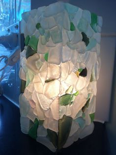 a vase made out of sea glass sitting on top of a table