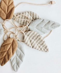 four leaf shaped ornaments hanging from strings on a white surface with string attached to them