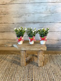 three small white flowers sitting on top of a wooden bench