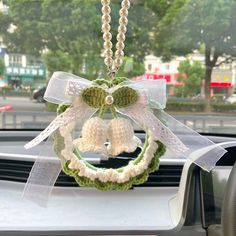 a crocheted wreath with bells hanging from it's front window in a car