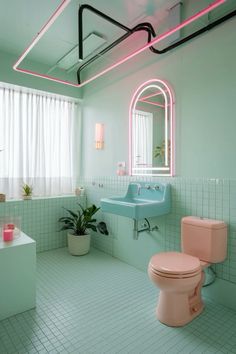 a pink toilet sitting next to a blue sink in a bathroom under a large mirror