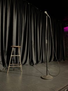 a chair and microphone in front of a black curtained stage with lights on it