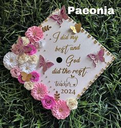 a graduation cap with flowers and butterflies on the top is shown in front of some green grass