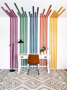 a room with a rug, desk and colorful striped wallpaper on the walls behind it