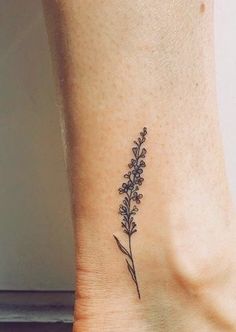 a small tattoo on the ankle of a woman's foot, with purple flowers