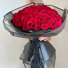 a woman holding a large bouquet of red roses