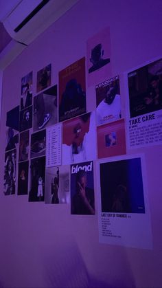 a wall covered in posters and pictures with purple lighting on it's side,