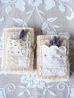 two pieces of cloth with lace and flowers on them are sitting on a tablecloth