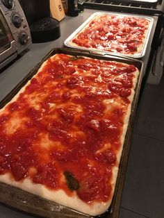 two pans filled with pizza sitting on top of a counter next to an oven