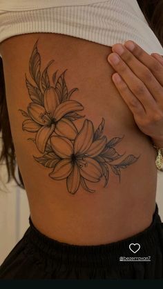 a woman's stomach with a flower tattoo on her side and the bottom part of her belly