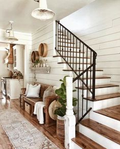 a living room filled with furniture and a stair case next to a wooden floor covered in rugs