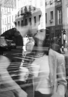 people are walking down the street in front of a store window with their reflection on it