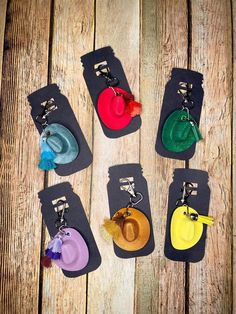 six different colored hats are on display in the shape of luggage tags with tassels attached to them