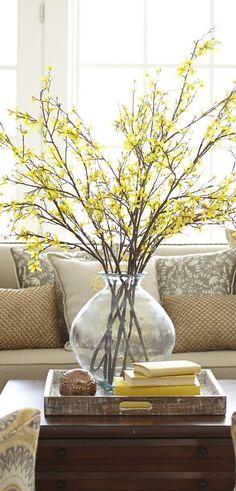 a living room filled with furniture and a vase full of yellow flowers on top of a coffee table