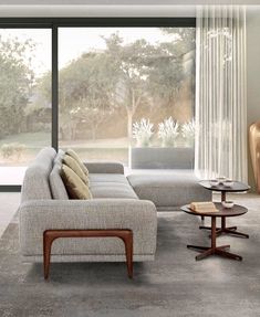 a living room filled with furniture next to a large glass window covered in trees and grass