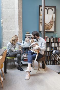 a man and two children are sitting at a table in front of bookshelves