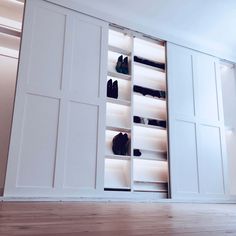 an open closet with several pairs of shoes on the bottom shelf and doors to the side