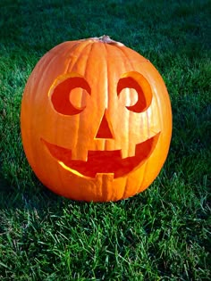 a carved pumpkin sitting in the grass with eyes drawn on it's face and mouth