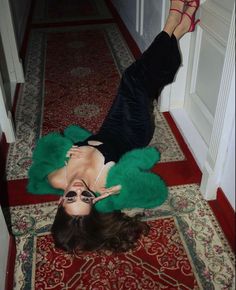 a woman is laying on the floor with her legs crossed and wearing green fur coat