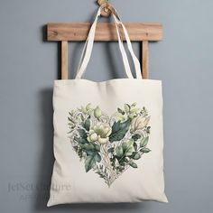 a white tote bag hanging from a wooden hanger on a gray wall with green leaves and flowers in the shape of a heart