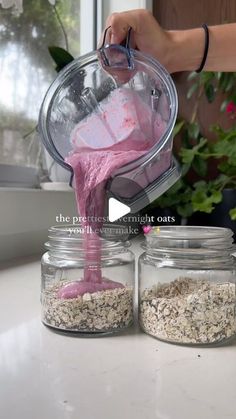 a person pouring pink liquid into two jars