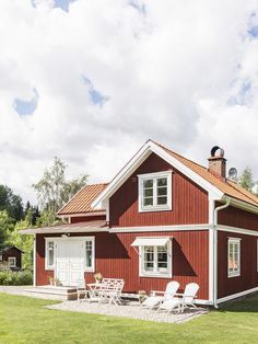 a red house sitting on top of a lush green field