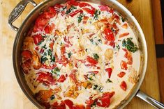 a pizza with tomatoes, cheese and spinach in a pan on a wooden table