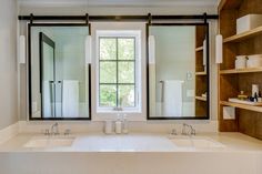 a bathroom with two sinks and three mirrors