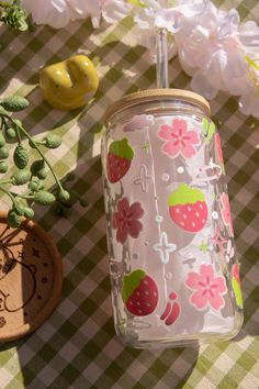 a glass jar with strawberries on it sitting next to some flowers and other items