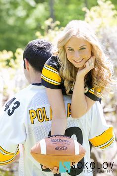 a woman holding a football while standing next to a man with his arm around her