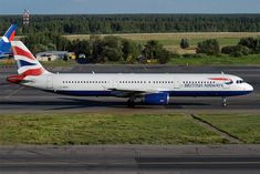 an airplane is parked on the tarmac near some grass and trees in the background