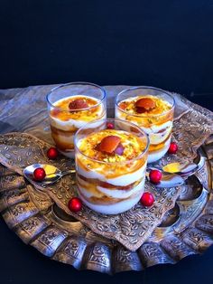 three desserts on a silver platter with red berries and gold trim around them