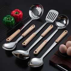 an assortment of kitchen utensils and spoons on a black table with ingredients