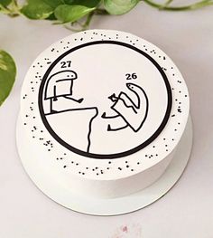 a white cake decorated with a drawing of two people on the face and one is looking at each other